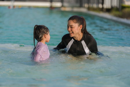 preschool child girl playing and swimming with her mother in the pool