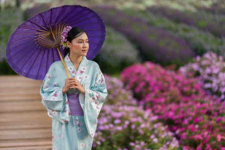 woman in yukata (kimono dress) holding umbrella with flower blooming in the garden