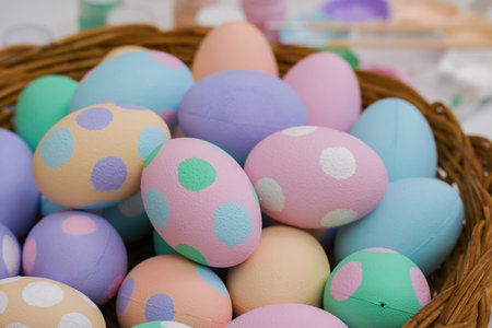 many colorful pastel decorated easter eggs in a small wooden basket and watercolor painting tool