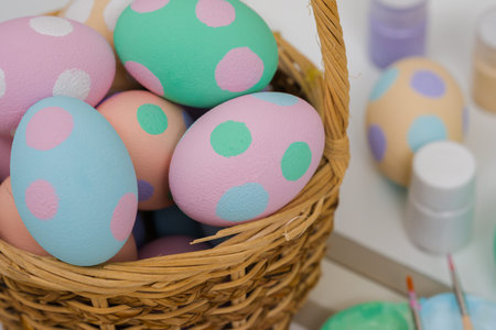 many colorful pastel decorated easter eggs in a small wooden basket and watercolor painting tool on...