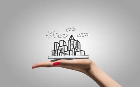 Drawing city skyscrapers on hand with smartphoneの写真素材
