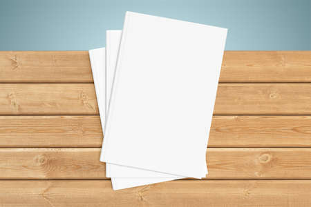 Three white copy-books are on the edge of a wooden tableの写真素材