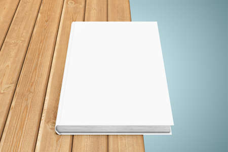 White textbook, situated on the edge of a wooden tableの写真素材