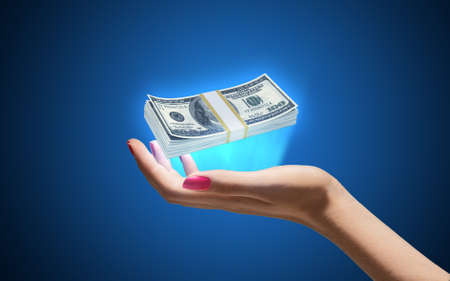 Pack of dollars on hand on blue backgroundの写真素材