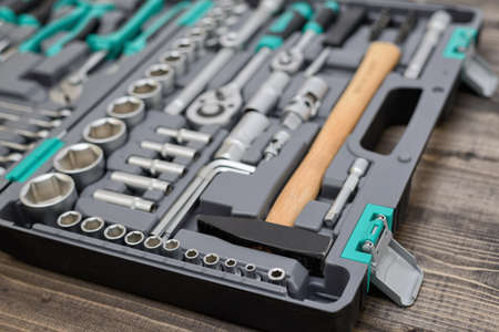 An open black toolbox with different instruments on wooden surfaceの写真素材