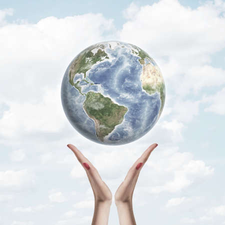 Earth in the air over hands on a background of sky and clouds. Concept of environmental protection, care for planetの写真素材