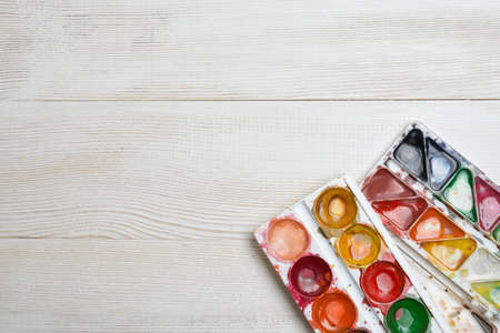 Used watercolor paints on a white wooden background. Top view of desktop.の写真素材