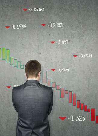 Businessman drawing on concrete wall financial and stock charts. Business, falling markets conceptの写真素材