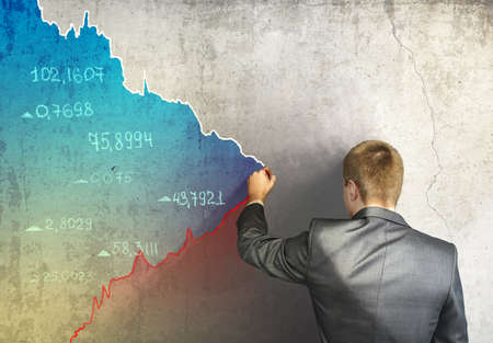Businessman drawing on concrete wall financial and stock charts. Business, falling markets conceptの写真素材