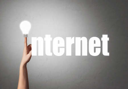 Hand with bright light bulb on the index finger in the form of letters and the word INTERNET on a...