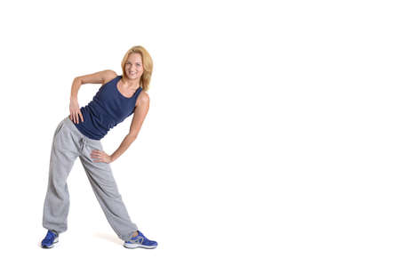 Beautiful smiling fitness woman wearing black sport pants and purple sport shoes isolated on white backgroundの写真素材