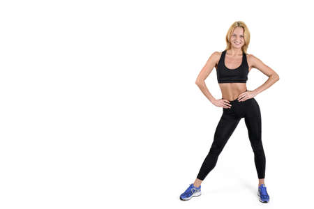 Beautiful smiling fitness woman wearing black sport pants and purple sport shoes isolated on white backgroundの写真素材