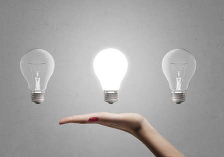 A woman's hand holding three light bulbs in her hand without touching them.の写真素材