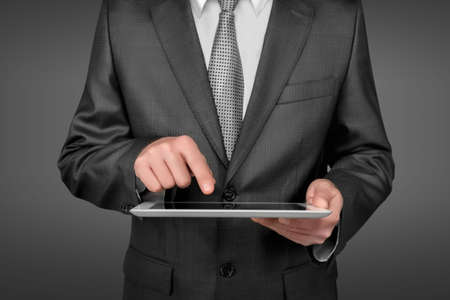 A businessman holding a digital tablet touching a screen of the digital tablet by his finger