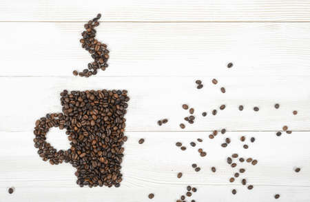 Top view coffee beans making a shape of mug hot coffee on wooden light surface.の写真素材