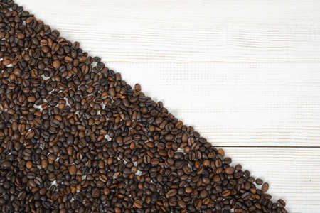 A wooden surface half backfilled with coffee beans on diagonally