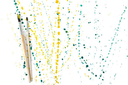 Two paint brushes with colorful gouache sprays and splashes on a white background.の写真素材