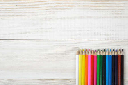 Set of sharp colorful pencils are in a row on a wooden blank board.の写真素材