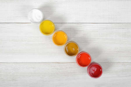 Light colors of gouache jars are diagonally on white background in top view.の写真素材