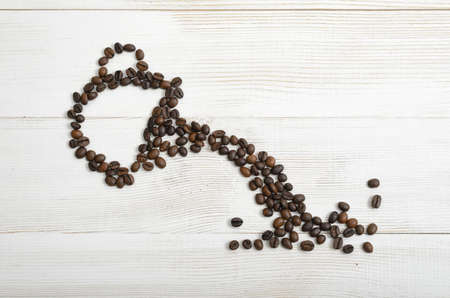 Top view of coffee beans making shape of mug from which pours a drink.の写真素材