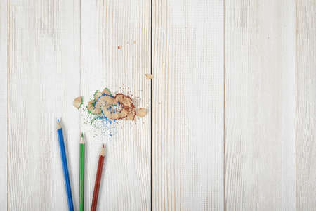 Green and blue colored pencils and its shavings on wooden plank.