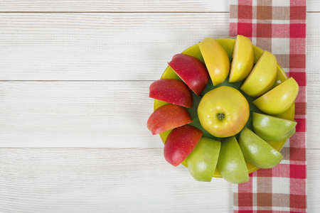 Yellow, green and red quartered apples laid out around the whole apple on a saucer.の写真素材