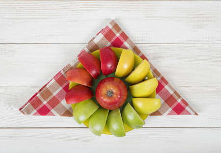 Yellow, green and red quartered apples laid out around the whole apple on a saucer. Table decoration.の写真素材