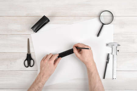 Workplace of draftsman equipped with pencil, ruler, pen, stapler, scissors and magnifying glass....
