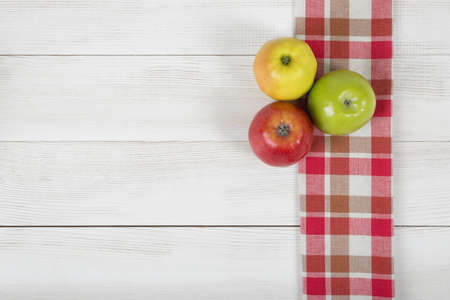 Colored whole apples placed on red checkered kitchen tablecloth. Top view.の写真素材