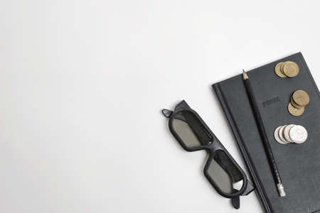 Flat lay of black notebook, pen, glasses and ruble coins on wooden surface with copy space on left side.の写真素材