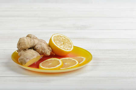 Composition of yellow lemon slices and ginger laid out on a saucer. Ingredients to take for colds.の写真素材