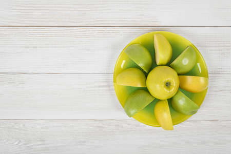 Ripe juicy yellow and green apples laid out around the whole apple on a saucer, placed with copy space.の写真素材