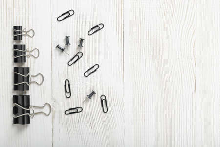 Black clips posted from biggest to smallest and thumbtacks are on a wooden surface with copy space on the right side.の写真素材