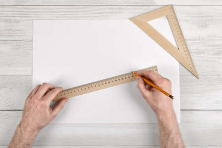 Close-up of draftsman hands holding centimeter ruler and pencil. Measuring process. Work place of draftsman.の写真素材
