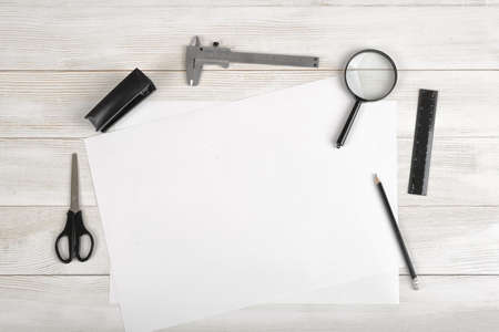 Workplace of constructor includes pencil, ruler, stapler, scissors, magnifying glass and white paper. Top view.の写真素材