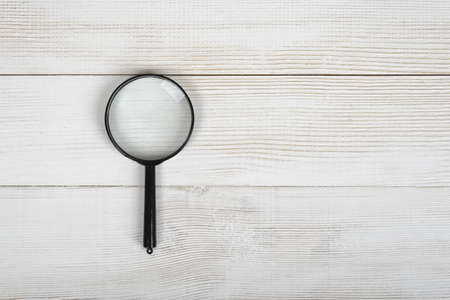 Top view of the magnifying glass lying  on wooden plank with open space on right side.の写真素材