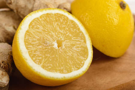 Yellow lemon slices and halves are on a cutting wooden boardの写真素材