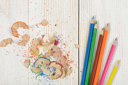 Flat lay of different colored pencils and shavings on white wooden table.の写真素材