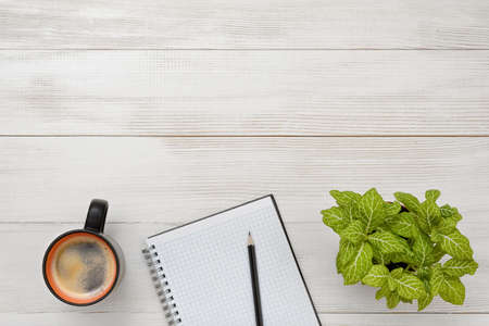Office workplace with green houseplant, cup of coffee and empty notebook. Increasing productivity in...
