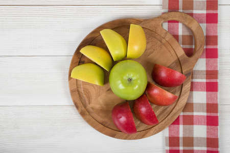 Apples lie on a wooden board and checkered kitchen tablecloth in top view. Table decoration. Healthy food. Improving health. Beating diarrhea and constipation. Boosting immune system.の写真素材