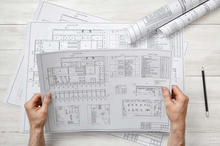 Hands of architect holding a drawing sketch. Workplace of architect. Engineering work. Construction and architecture. Architect drawing. Project.の写真素材