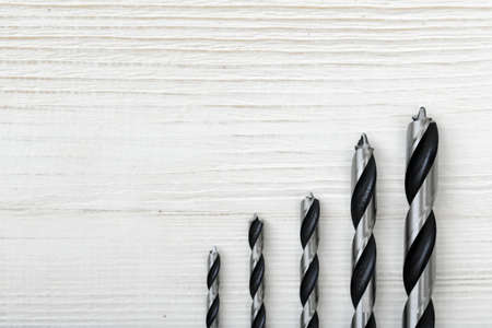 Different size drills posted from the highest to the lowest on a wooden surface. Top view composition. Construction instrument and tool. Set of drills. Mend and repair.の写真素材