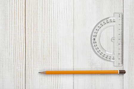 Layout with protractor and pencil on wooden surface. Top view composition. Measuring process. Work place of draftsman, architect, constructor. Engineering work. Construction and architecture. Working stuff.の写真素材
