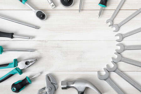 Set of different type of construction instruments and tools placed on wooden surface with copy space at the center. Top view composition. Mend and repair. Set of tools. Home tool kit. Everyday instruments. Work stuff.の写真素材