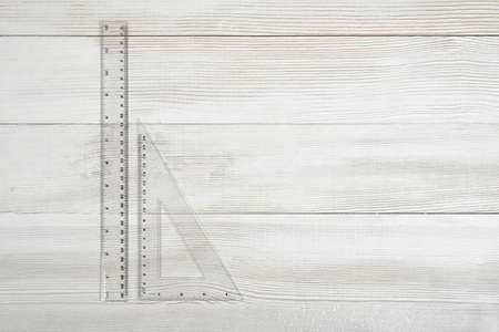 Plastic triangular ruler and straight-edge ruler on wooden table. Mathematics. Science. Calculation...
