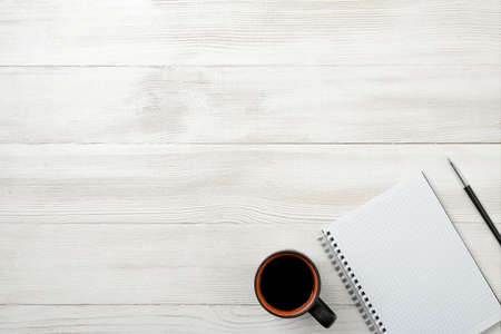 Top view of open empty notebook and black pen on it with cup of hot coffee with copy space. Workplace of office man. Readiness for the new. First work day. Office stuff. Willingness to work overtime. Conductive working environment. Increasing productivityの写真素材