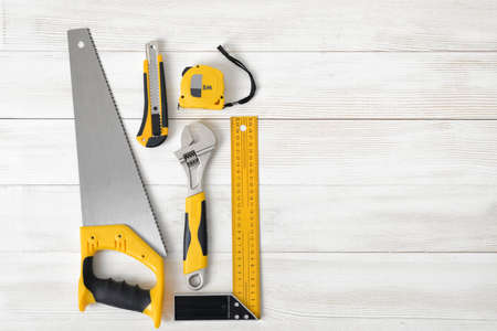 Building tools including centimeter ruler, wrench and cutter placed in the left side on wooden...