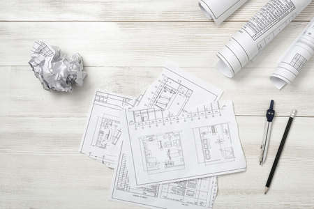 Rolls of drawing sketches, pencil and compass are on wooden surface.. Top view compositin. Workplace...