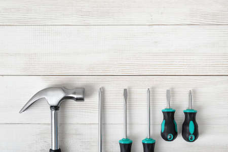 Top view of construction tools including hammer and different sized screwdrivers on wooden surface with open space. Tools for carpentry work. Type of fastener. Mend and repair. Parts for repair.の写真素材