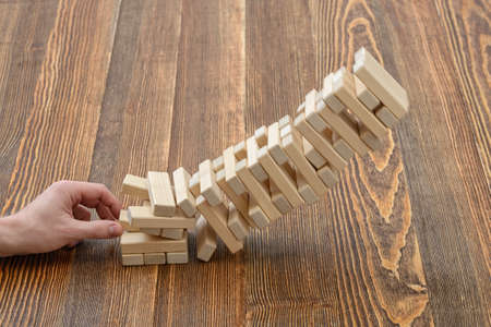 Close-up hands of man pulls out wooden bricks. Removing blocks from a tower. Keeping balance. Full concentration. Entertainment activity. Game of physical and mental skill. Close-up photo.の写真素材